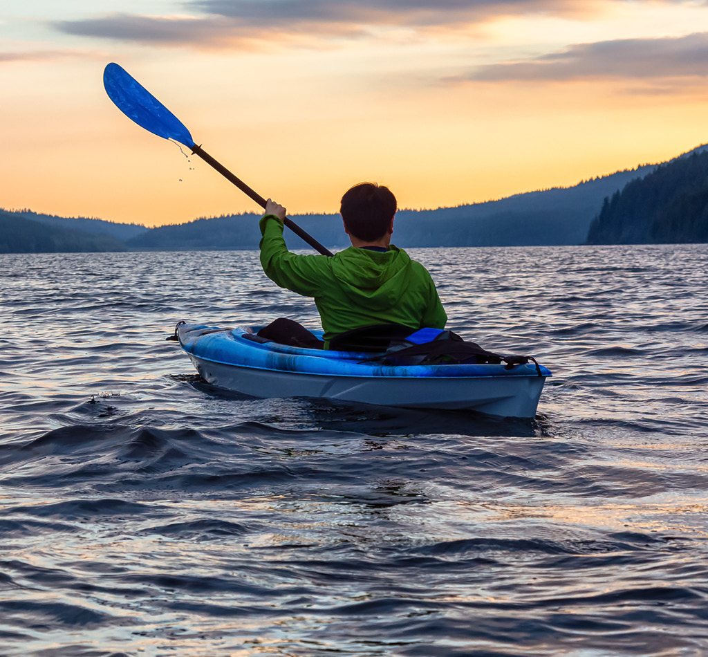 Person Kayaking on a scenic lake at sunset in Golden Ears Provincial Park, near Vancouver, British Columbia, Canada.